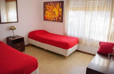 a bedroom with two beds and a red blanket at Casa con pileta in Villa Carlos Paz