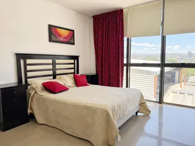 a bedroom with a bed with red pillows and a window at Torre Melos Carlos Paz in Villa Carlos Paz