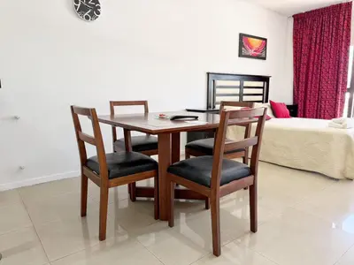 a dining room table with four chairs and a bed at Torre Melos Carlos Paz in Villa Carlos Paz