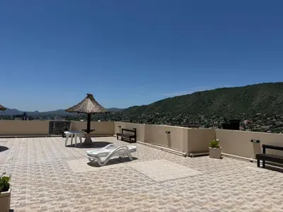 a patio with a table and an umbrella on a roof at Torre Melos Carlos Paz in Villa Carlos Paz