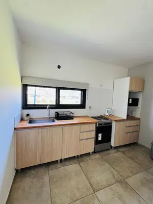 a kitchen with wooden cabinets and a sink and a window at Duplex con pileta frente a lago Los Molinos in La Estancia