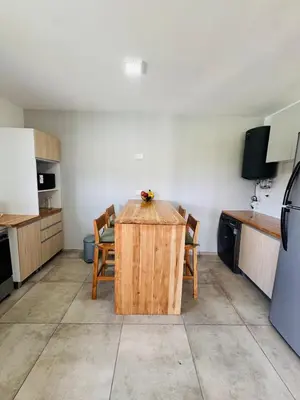 a kitchen with a wooden table and chairs at Duplex con pileta frente a lago Los Molinos in La Estancia