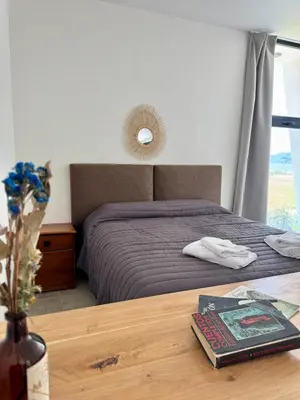a bedroom with a bed and a table with a book at Duplex con pileta frente a lago Los Molinos in La Estancia