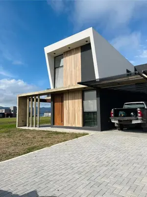a house with a car parked in the driveway at Duplex con pileta frente a lago Los Molinos in La Estancia