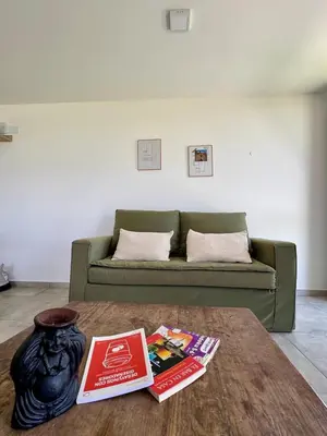 a living room with a couch and a table with books at Duplex con pileta frente a lago Los Molinos in La Estancia