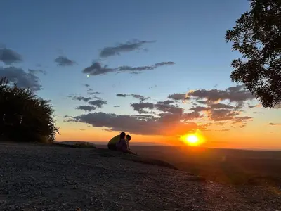 two people sitting on a hill watching the sunset at Fuego in Nono
