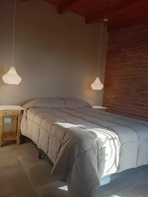 a bedroom with a large bed and two pendant lights at Complejo DOS LUNAS in La Porteña