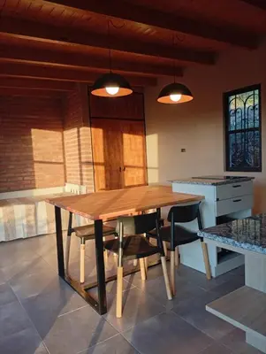 a kitchen with a wooden table and chairs at Complejo DOS LUNAS in La Porteña