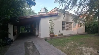 a small white house with a potted plant in a yard at Casa con pileta y jardín - 3 dormitorios in Villa Carlos Paz