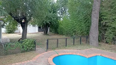 a swimming pool in a yard with a fence and trees at Casa con pileta y jardín - 3 dormitorios in Villa Carlos Paz