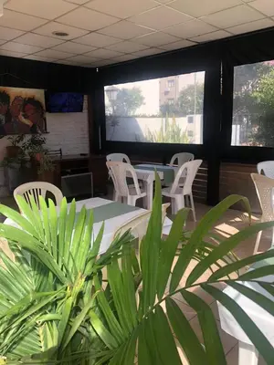 a restaurant with white chairs and tables and a plant at Nuevo Chalet Suizo in Villa Carlos Paz