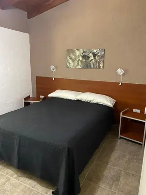 a bedroom with a large bed with two lamps on it at LA TORRE - Complejo de cabañas in Villa Rumipal