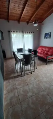 a dining room with a table and chairs and a red couch at LA TORRE - Complejo de cabañas in Villa Rumipal