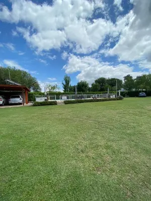 a large grassy field with a building in the background at LA TORRE - Complejo de cabañas in Villa Rumipal