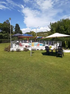 two chairs and a table with umbrellas in a park at LA TORRE - Complejo de cabañas in Villa Rumipal