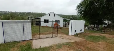 a white house with a gate in a field at Xaraba in Villa Parque Siquiman