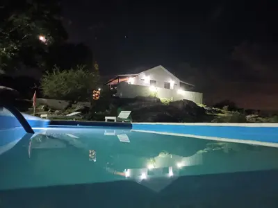 a swimming pool at night with a house in the background at Xaraba in Villa Parque Siquiman