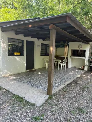 a small white house with a patio with a table at AlCarajo in Villa Yacanto