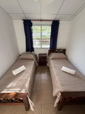 two beds in a small room with a window at Cabañas Marquetti 2 in Potrero de Garay