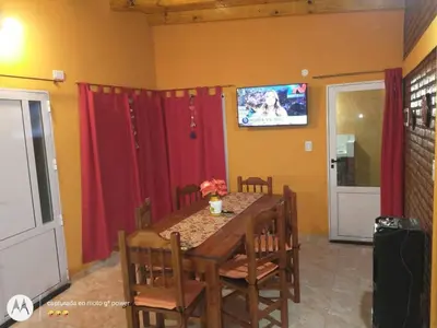 a dining room table with red curtains and a tv at Nuestro sol-ar in Tanti
