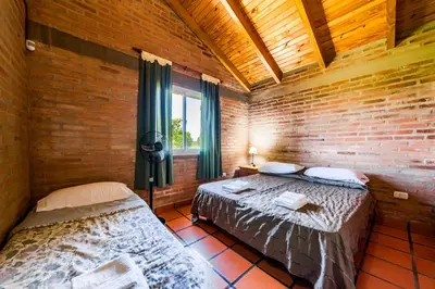 a bedroom with two beds and a brick wall at El Encuentro Casa de Campo in Río Cuarto