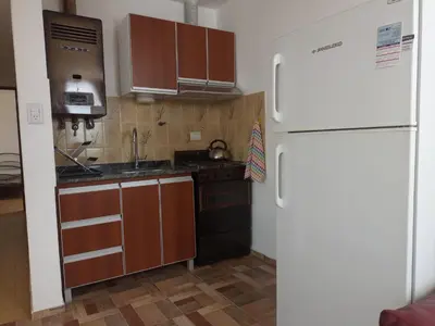 a kitchen with brown cabinets and a white refrigerator at Luminoso in Villa Carlos Paz