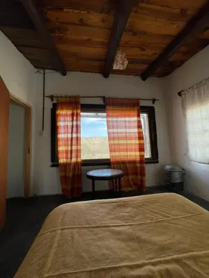a bedroom with a bed and a table and a window at La Vision, Casa de campo in Villa Quillinzo