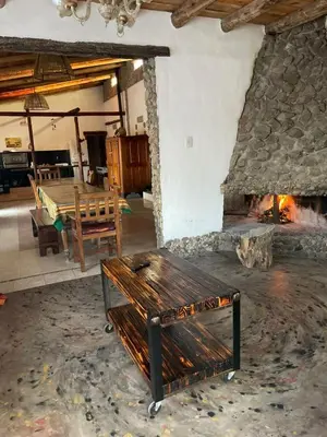 a living room with a stone fireplace and a wooden bench at La Vision, Casa de campo in Villa Quillinzo