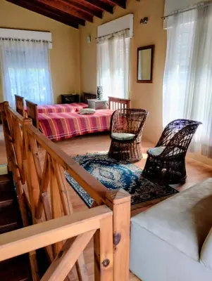 a living room with two chairs and a bed at Emilia Casa de Campo in Santa Rosa de Calamuchita