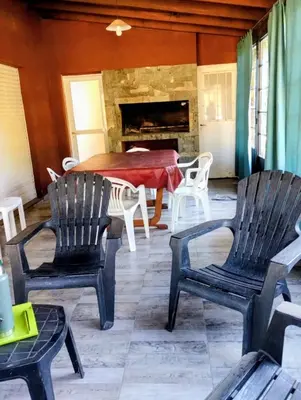 a living room with chairs and a table and a fireplace at Emilia Casa de Campo in Santa Rosa de Calamuchita