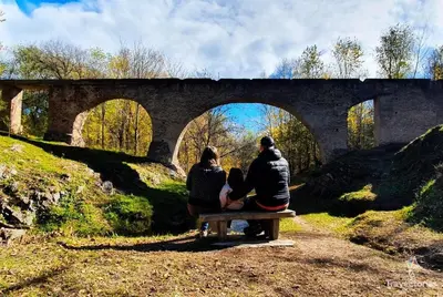 three people sitting on a bench under a bridge at Emilia Casa de Campo in Santa Rosa de Calamuchita