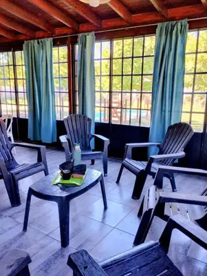 a living room with chairs and a table and windows at Emilia Casa de Campo in Santa Rosa de Calamuchita