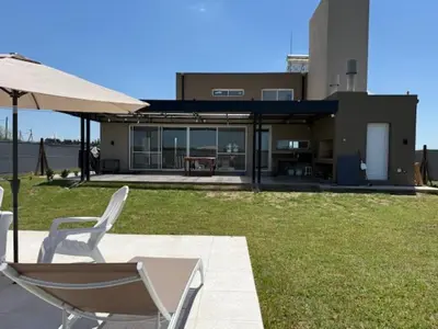 two chairs and an umbrella in front of a house at HOUSE SOUTH en AQUAVISTA VILLA RESIDENCIAL in Malagueño