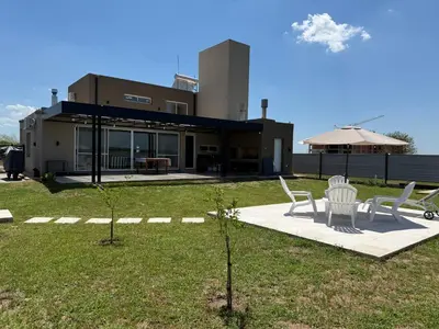 a house with two white chairs and a patio at HOUSE SOUTH en AQUAVISTA VILLA RESIDENCIAL in Malagueño
