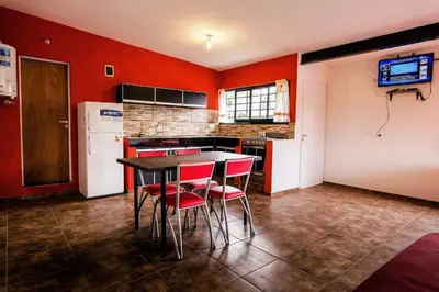 a kitchen with red walls and a table and chairs at Monoambiente los ceibos in Villa Santa Cruz del Lago