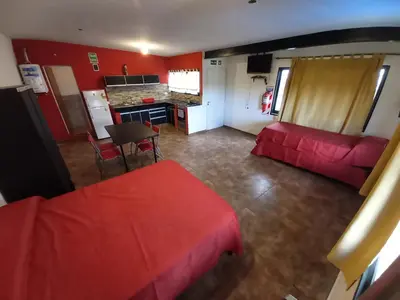 a living room with a red couch and a kitchen at Monoambiente los ceibos in Villa Santa Cruz del Lago