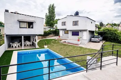 a villa with a swimming pool in front of a house at Casita los ceibos in Villa Santa Cruz del Lago