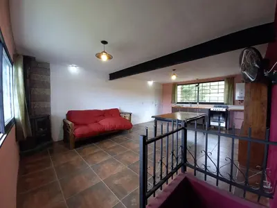 a living room with a red couch and a kitchen at Casita los ceibos in Villa Santa Cruz del Lago
