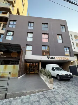 a building with a car parked in a parking lot at Departamento en Villa Carlos Paz in Villa Carlos Paz
