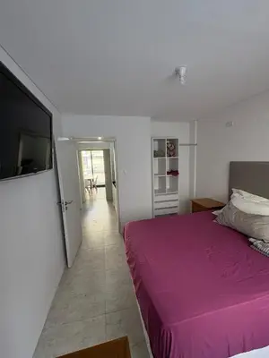 a bedroom with a purple bed and a television at Departamento en Villa Carlos Paz in Villa Carlos Paz