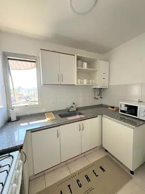 an empty kitchen with white cabinets and a window at Teacher Grace - Departamento 2 dormitorios en Nueva Córdoba in Cordoba