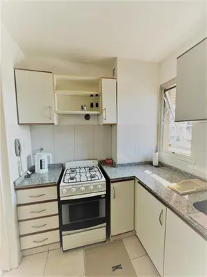 a kitchen with white cabinets and a stove top oven at Teacher Grace - Departamento 2 dormitorios en Nueva Córdoba in Cordoba