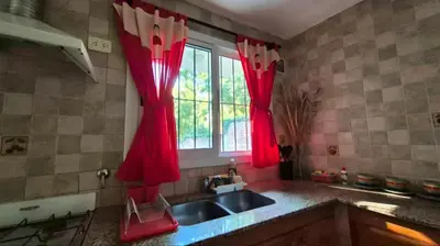 a kitchen with red curtains over a sink and a window at Departamento tranquilo cerca de la terminal Villa General Belgrano a 5 cuadras del centro in Villa General Belgrano