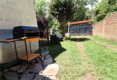 a barbecue grill in a yard next to a building at Departamento tranquilo cerca de la terminal Villa General Belgrano a 5 cuadras del centro in Villa General Belgrano