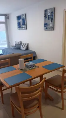 a dining room table with two chairs and a bed at Dpto Premium Costanera cochera y patio privado in Villa Carlos Paz