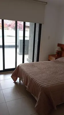 a bedroom with a bed and a large window at Dpto Premium Costanera cochera y patio privado in Villa Carlos Paz