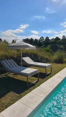 two benches and an umbrella next to a swimming pool at Aire in La Estancia