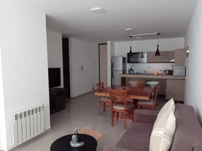 a living room and kitchen with a couch and a table at Departamento Paseo Quattro in Villa Carlos Paz