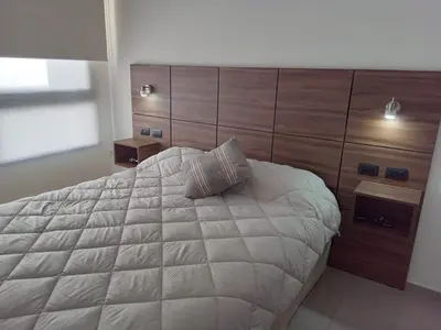 a bedroom with a large white bed with a wooden headboard at Departamento Paseo Quattro in Villa Carlos Paz