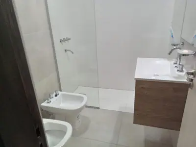 a white bathroom with a toilet and a sink at Departamento Paseo Quattro in Villa Carlos Paz